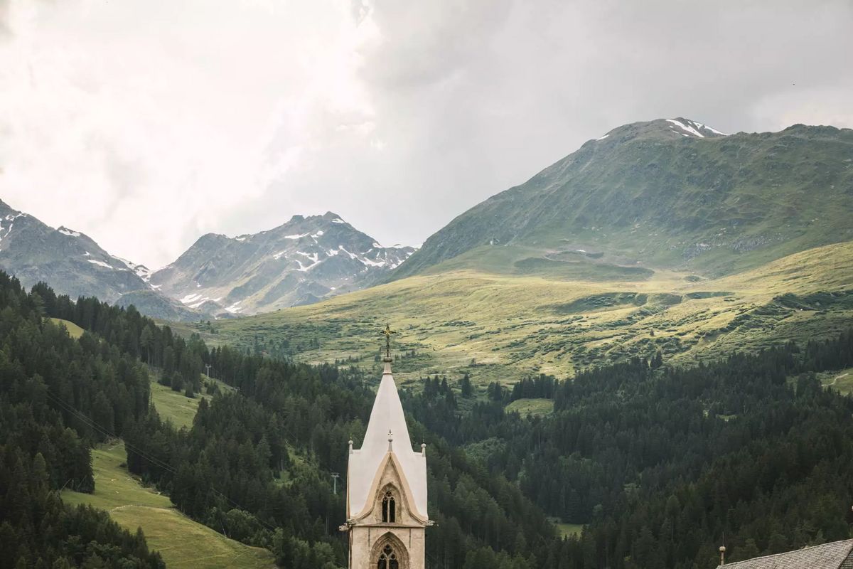 Der Kirchturm von Sefaus ragt über der bergigen Landschaft hinaus
