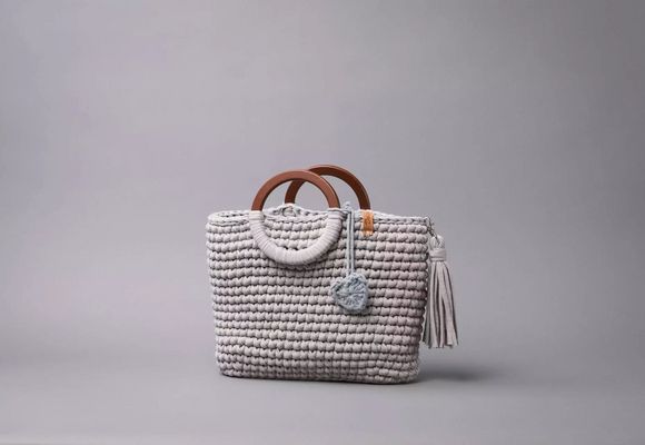 Eine Tasche aus grauem Stoff mit Holzgriffen